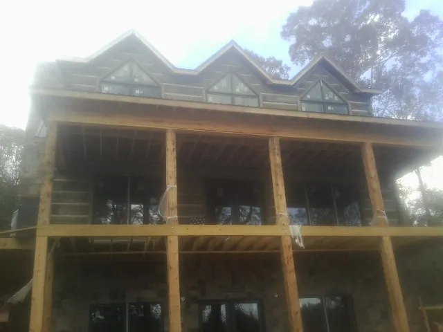 Dormers and porch framing on a large log home under construction — Roof Coating work by our crew in Nachusa