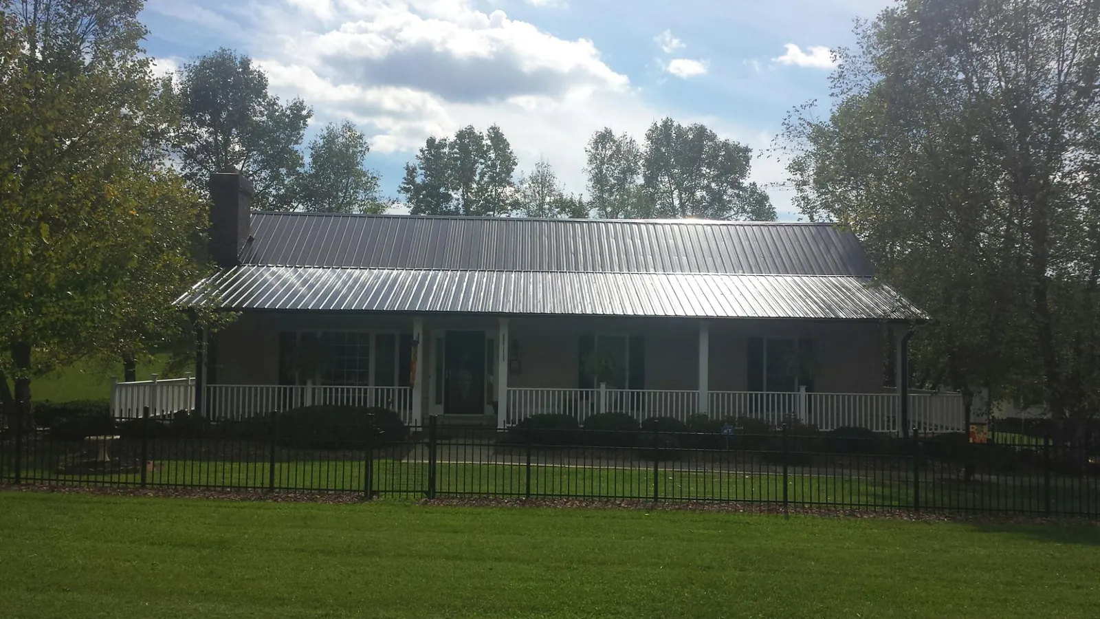 Gray metal roof on a brick ranch with a full width front porch — Gutter Guard Installation work by our crew in Nachusa
