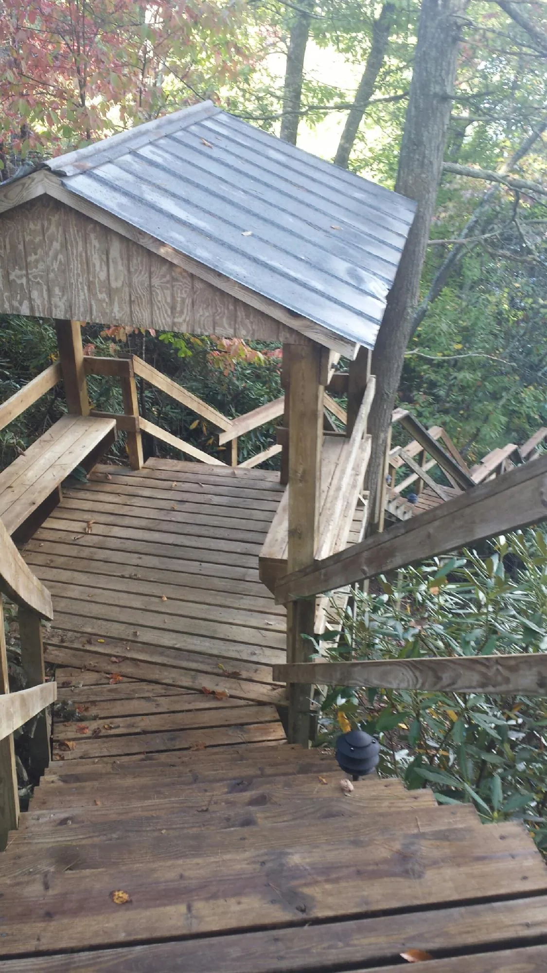 Metal roofed shelter over wooden steps on a wooded walkway — Skylight Repair & Installation work by our crew in Nachusa