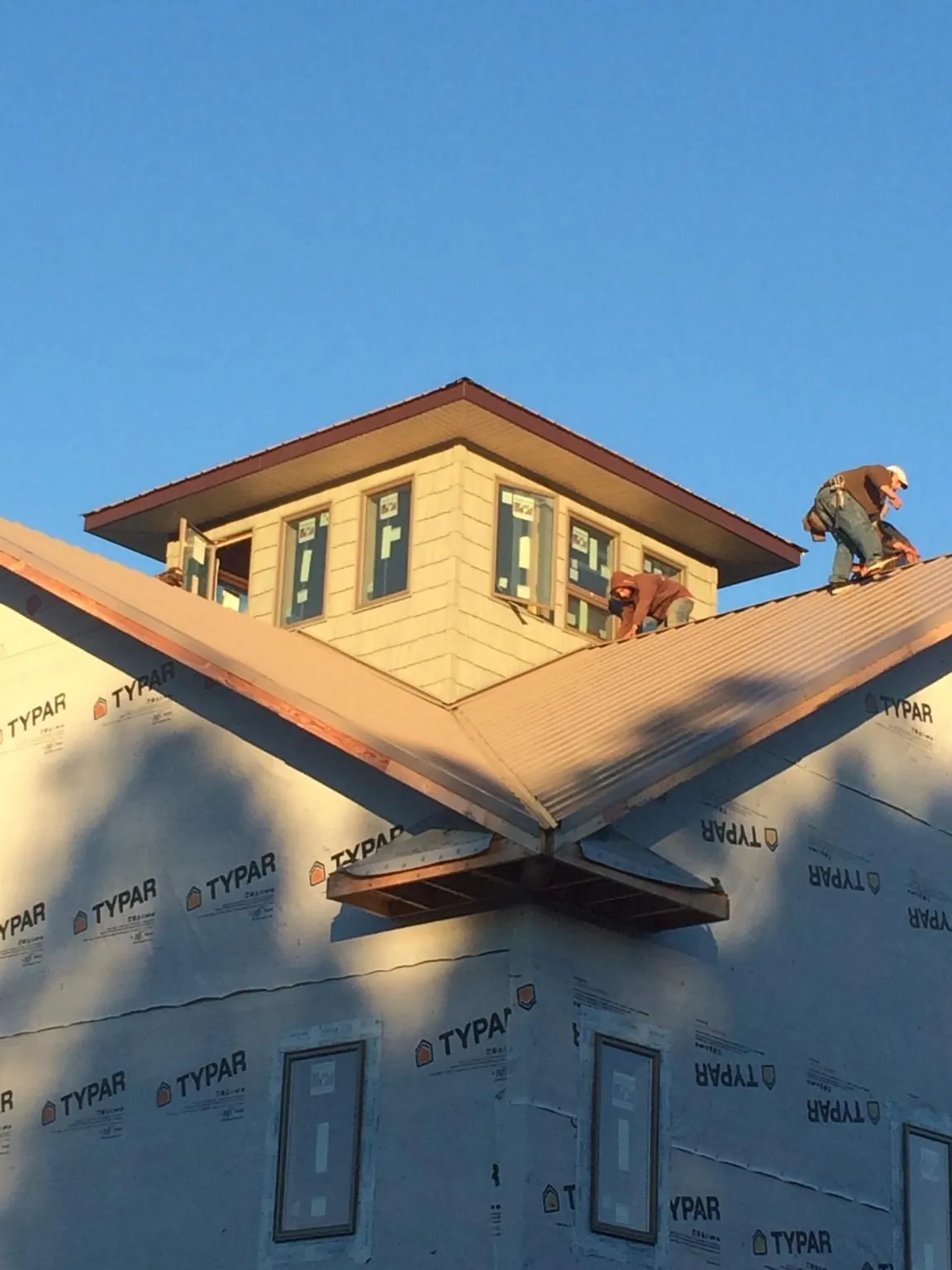 Roofers working around a rooftop cupola on a new metal roof at sunset — Roof Waterproofing in Nachusa by Roofing Brothers